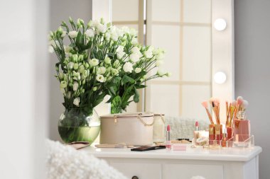 Dekoratif kozmetik ürünleri ve vazo. Soyunma odasındaki masada çiçekler.