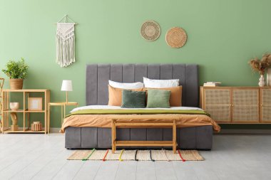 Şık bir yatak odasında rahat bir yatak, lamba ve komodin.