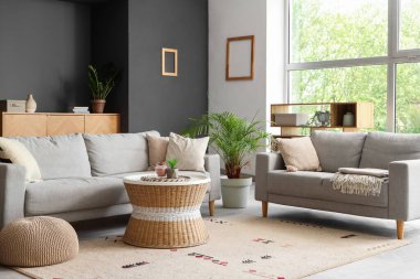 Gri kanepeleri ve kahve masası olan modern oturma odasının içinde.