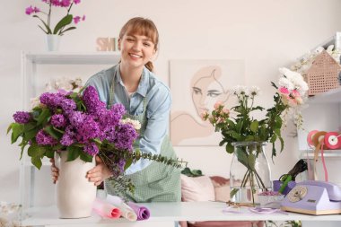 Çiçek stüdyosunda vazo dolusu leylağı olan bir çiçekçi.