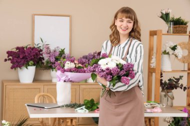 Çiçekçide çiçek buketi, leylak ve kasımpatı tutan kadın.