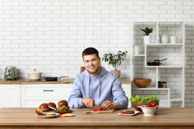 Genç adam mutfakta domates doğruyor.
