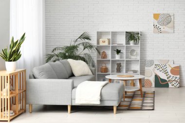 Gri kanepesi, raf ünitesi ve sehpası olan modern oturma odasının içinde.