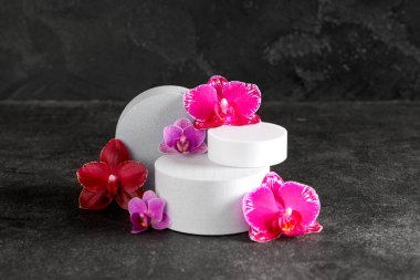 Siyah arka planda güzel orkide çiçekleri olan dekoratif podyumlar