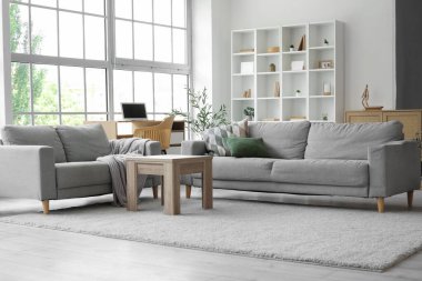 Oturma odasının içinde kanepeler, masa ve işyeri var.