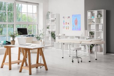 Çalışma yerleri, masaj koltuğu ve raf üniteleri olan bir hastane.