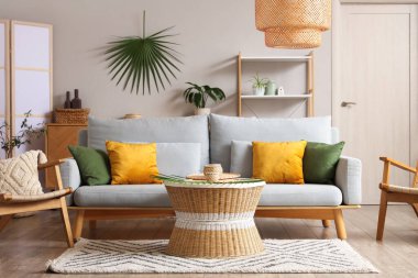 Oturma odasının içinde kanepe, koltuk ve rattan masa var.