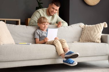 Genç baba evdeki oğluna ev ödevlerini anlatıyor.