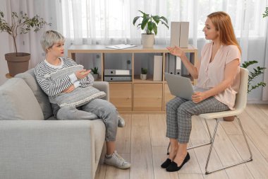 Koltukta yastıklı üzgün genç kız ofiste psikologla konuşuyor.