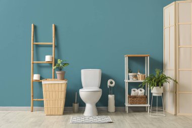 Tuvalet, çöp tenekesi, merdiven ve raf ünitesi mavi duvarın yanında.