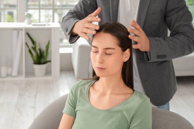 Psikolog ofisinde hipnoz seansı sırasında koltukta oturan genç bir kadın.