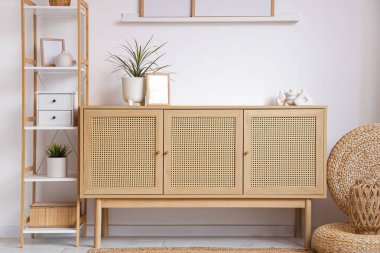 Ahşap çekmeceler ve raflar. Oturma odasının iç tarafındaki beyaz duvarın yanında bitkiler var.