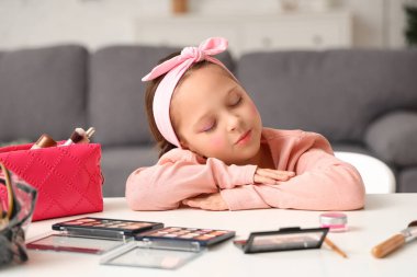 Oturma odasındaki masada göz falı ve kozmetik çantalı şirin küçük kız.