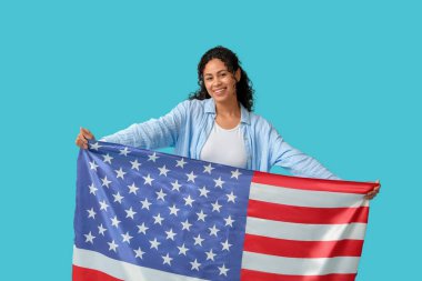 Mavi arka planda Amerikan bayrağı olan güzel, mutlu, Afro-Amerikan bir kadın.