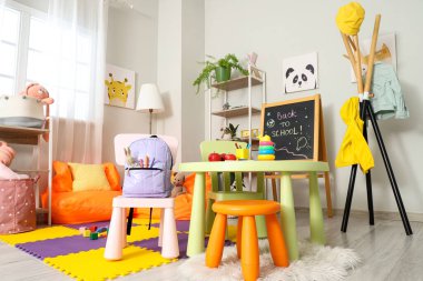 Armut koltuk, oyuncak ve sırt çantalı çocuk odasının içinde.