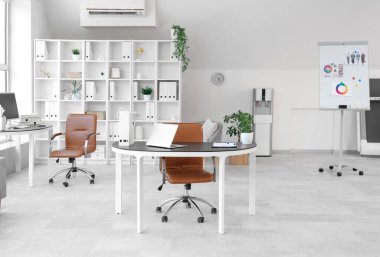 Çalışma alanları, raf ünitesi ve koltukları olan açık uzay ofisinin içi