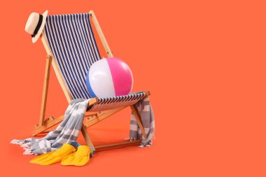 Turuncu arka planda iskemle ve plaj aksesuarları. Seyahat kavramı