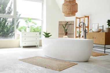 Küvet, ahşap raf ünitesi, çekmeceler ve hafif banyonun içindeki saksılar.