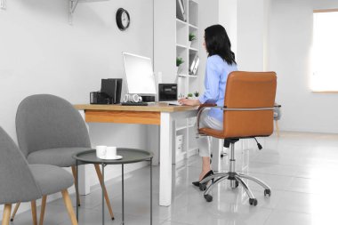 İş yerinde modern bilgisayarla çalışan genç bir kadın.