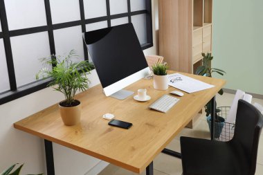 Rahat işyeri, modern bilgisayar, raf ünitesi ve koltuğu olan güzel bir ofis.