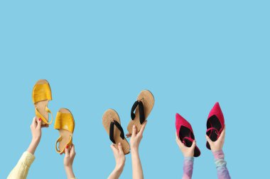 Mavi arka planda terlikleri ve topukları olan kadın elleri.