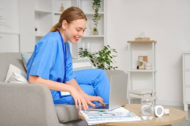 Genç bayan tıp öğrencisi modern bilgisayarla evde çalışıyor.