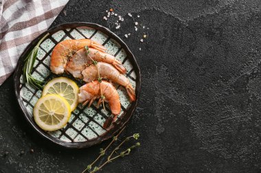 Lezzetli haşlanmış karides, biberiye ve limonlu siyah arka plan.