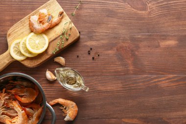 Ahşap arka planda lezzetli haşlanmış karidesli yemek ve tencere.