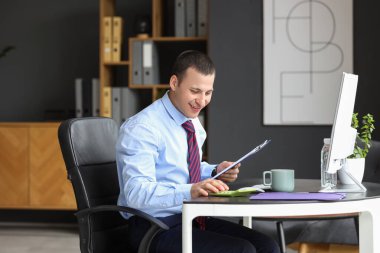 Ofiste hesap makinesiyle çalışan erkek muhasebeci.