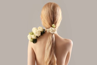 Gri arka planda çıplak gül buketi olan güzel genç bir kadın.