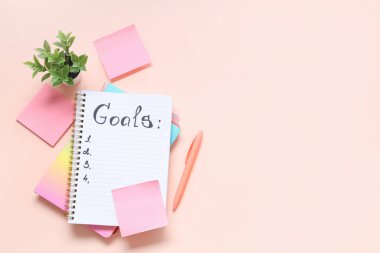 Pembe arka plandaki hedeflerin, defterlerin ve yapışkan notların listesi
