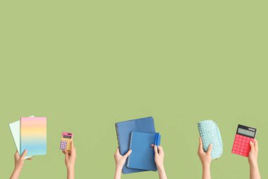 Yeşil arka planda okul ekipmanları olan kadın eller.