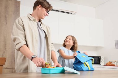 Babasıyla birlikte küçük bir kız, mutfakta beslenme çantası hazırlıyor.