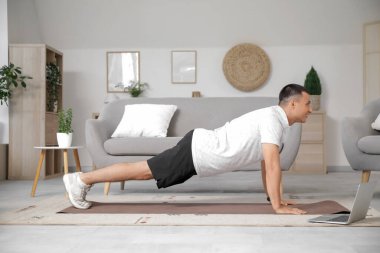 Evde dizüstü bilgisayar eğitimi alan genç bir sporcu.