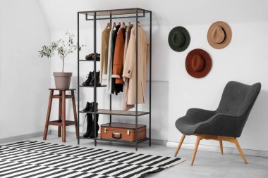 Elbise askısı, şapkası ve koltuğu olan soyunma odasının içinde.