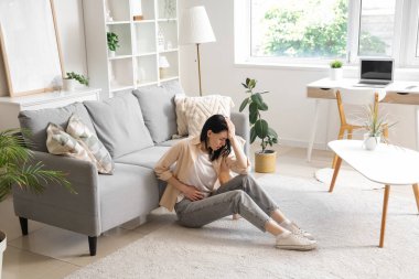 Evde şiddetli karın ağrısı çeken genç bir kadın var.