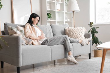 Evde şiddetli karın ağrısı çeken genç bir kadın var.