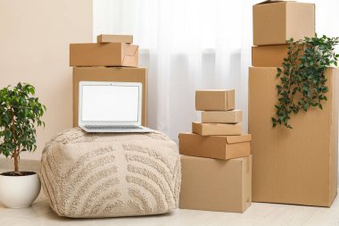 Boş dizüstü bilgisayar pouf üzerinde kutuları odanın penceresinin yakınına taşır