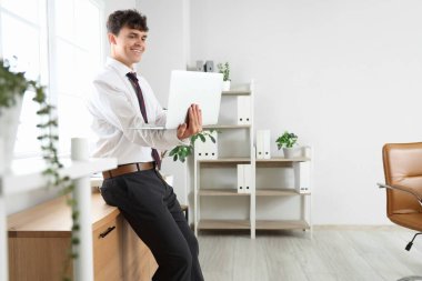 Erkek muhasebeci ofiste modern dizüstü bilgisayar kullanıyor.