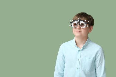 Yeşil arka planda optik deneme çerçevesinde küçük bir çocuk