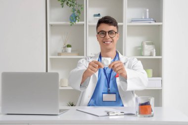 Genç doktor klinikte prezervatif gösteriyor.