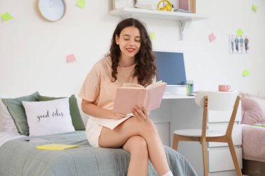 Yurt odasında kitap okuyan kız öğrenci.