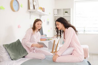 Yurt odasında tablet bilgisayar kullanan kız öğrenciler