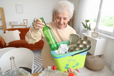 Evinde çöp kutusuyla çöp toplayan son sınıf öğrencisi bir kadın.