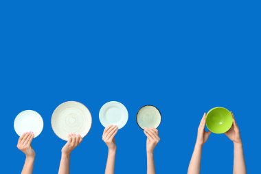 Mavi arkaplanda boş tabakları tutan eller