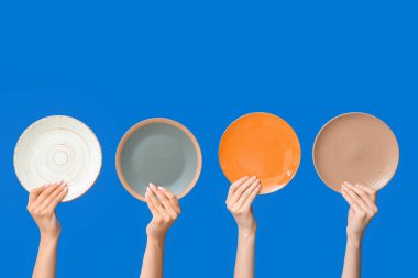 Mavi arkaplanda boş tabakları tutan eller