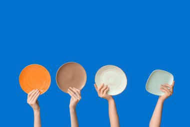 Mavi arkaplanda boş tabakları tutan eller