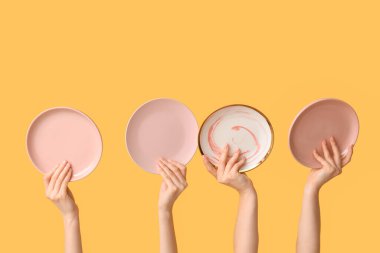 Sarı arkaplanda boş tabakları tutan eller