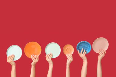 Kırmızı arkaplanda boş tabakları tutan eller