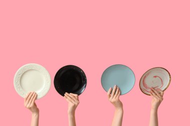 Pembe arka planda boş tabakları tutan eller